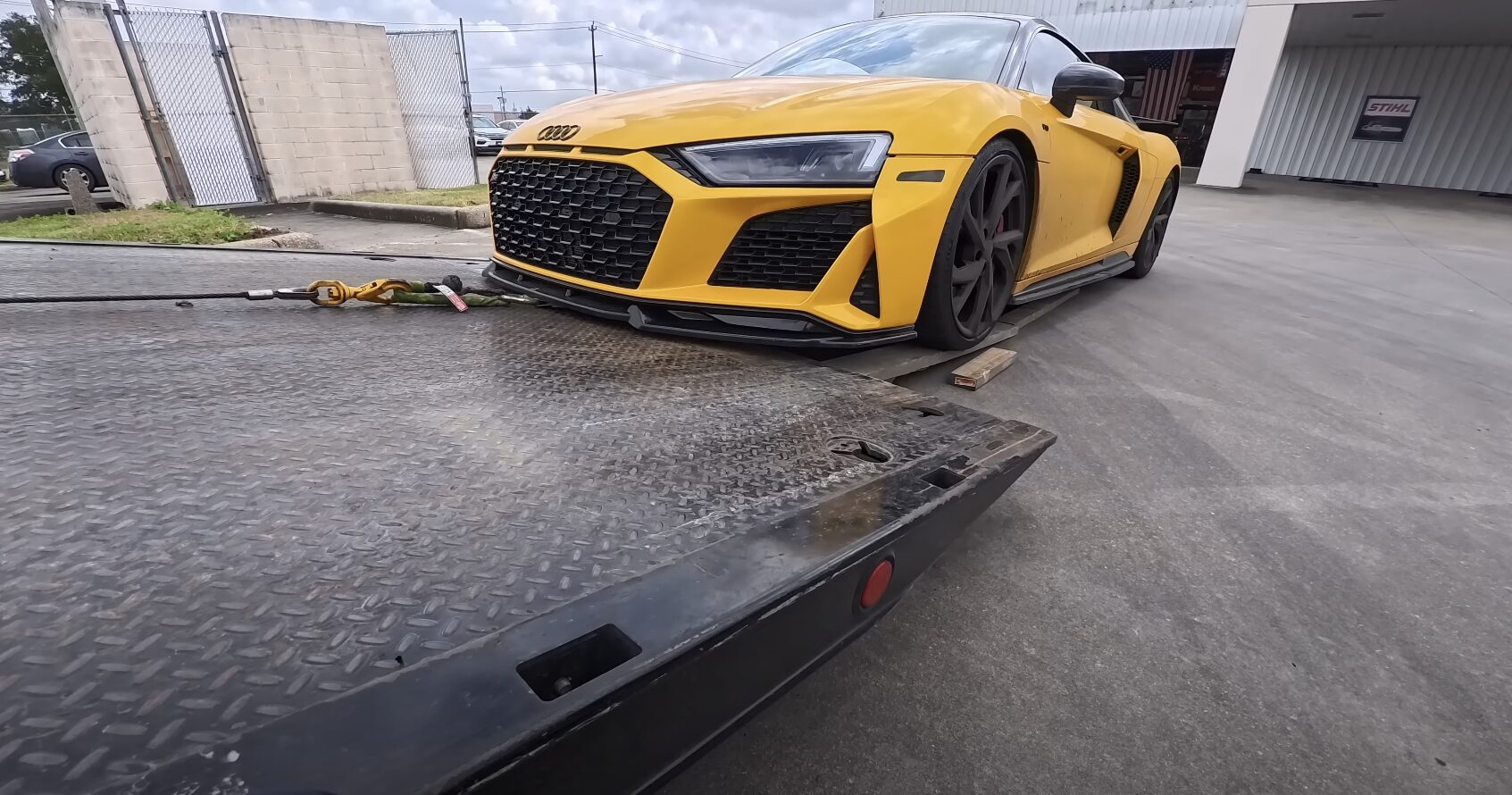 Yellow sports car being loaded onto flatbed tow truck with professional towing equipment